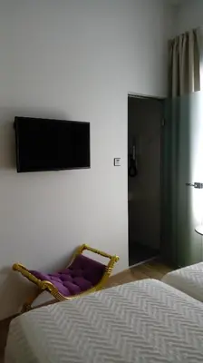 a bedroom with a chair with a tv on the wall at 9 Muses Hotel in Larnaka