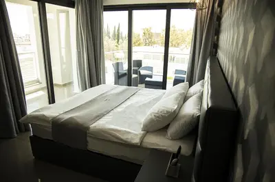 a bedroom with a bed and a large window at Jimmy's Suites in Larnaka