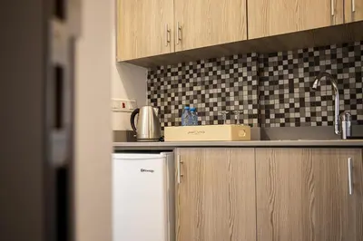 a kitchen with wooden cabinets and a white refrigerator at Jimmy's Suites in Larnaka