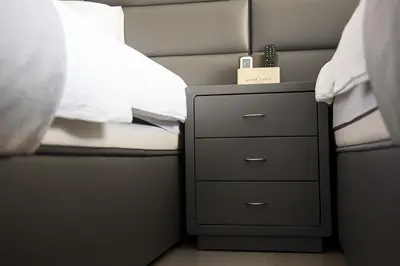 a bedroom with a bed and a night stand with a drawer at Jimmy's Suites in Larnaka