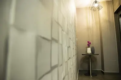 a hallway with a white tiled wall and a table at Jimmy's Suites in Larnaka