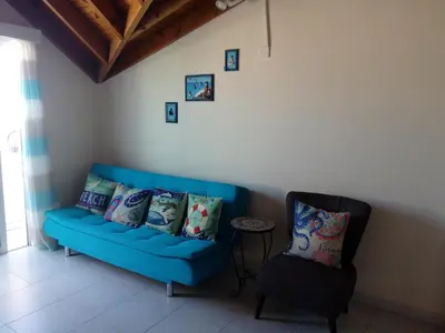 a living room with a blue couch and a chair at Lighthouse in Larnaka