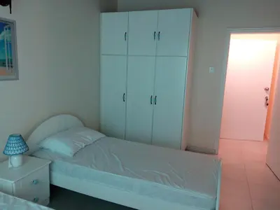 a bedroom with a bed with white cabinets and a lamp at Lighthouse in Larnaka