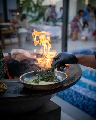a person cooking food in a pan on a grill at Napa Hills Seaview Villas in Ayia Napa