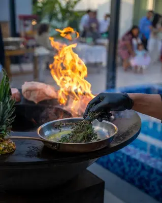 a person is cooking food in a pan on a grill at Napa Hills Seaview Villas in Ayia Napa