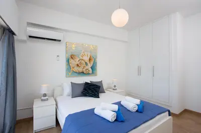 a white bedroom with a bed with blue sheets at White Arches Apt #1 by TrulyCyprus in Limassol