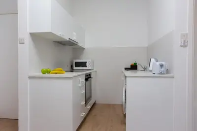 a white kitchen with white cabinets and a microwave at White Arches Apt #1 by TrulyCyprus in Limassol