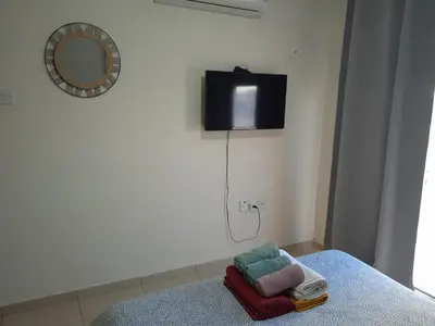 a room with a bed with a tv on the wall at Xylophagou Larnaca Ayia Napa 1 bedroom apartment in Xylophaghou