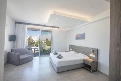 a bedroom with a bed and a chair and a window at Pavlinia Hotel & Apartments in Ayia Napa