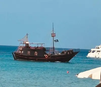 a black boat floating in the water at PALLINIO COURT 402 Fig Tree Bay- Protaras Beach, IASONOS STR 7A in Protaras