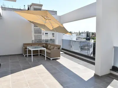 a patio with a couch and an umbrella on a roof at BAZ TOWER in Nicosia