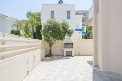 a courtyard with a tree and a white building at Protaras View Villa 5 in Protaras
