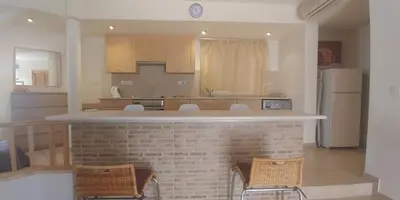 a kitchen with a bar with chairs and a refrigerator at Palm beach 14 in Limassol