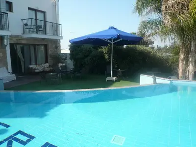 a blue swimming pool with an umbrella and a patio at Esperando in Maroni