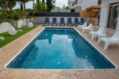 a swimming pool with chairs and a table and a house at Villa Fortuna in Ayia Napa