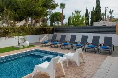 a swimming pool with chairs and a swimming pool at Villa Fortuna in Ayia Napa