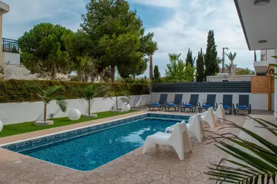 a swimming pool with white chairs and a pool at Villa Fortuna in Ayia Napa