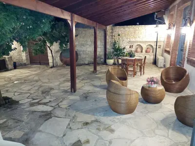 a patio with wooden chairs and a table and a stone floor at Evanthia's Stone House in Koilani