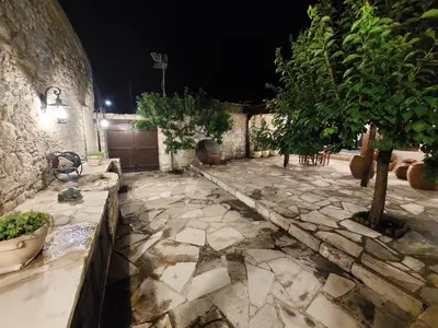 a stone courtyard with trees and a stone wall at Evanthia's Stone House in Koilani
