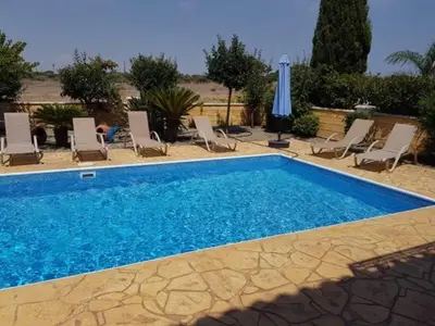 a swimming pool with chairs and an umbrella at Sunrise Villa in Ayia Napa