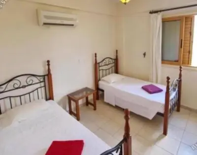 a bedroom with two beds and a table and a window at Sunrise Villa in Ayia Napa