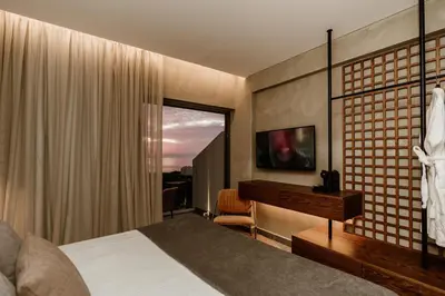 a bedroom with a bed and a desk and a window at Cavo Zoe Seaside Hotel in Protaras