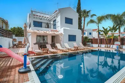 a swimming pool with chairs and a house at Amphitrite Villa in Paralimni