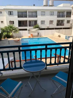a balcony with a table and chairs and a swimming pool at Napa Blue Apartment, XXL Pool,in Hearth of Ayia Napa in Ayia Napa