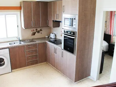a kitchen with wooden cabinets and a stove top oven at Panorama Beach House, 5 meters to the sea in Pervolia