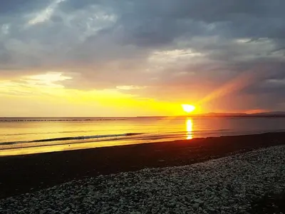 a sunset on a beach with the sun setting at Panorama Beach House, 5 meters to the sea in Pervolia