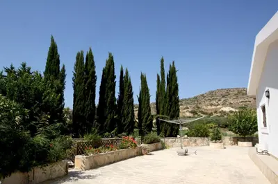 a garden with trees and a hill in the background at Pissouri Bay Bungalow in Pissouri
