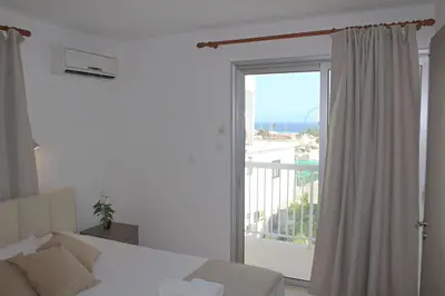 a bedroom with a bed and a balcony with a window at Maria Zintili Apartments in Ayia Napa