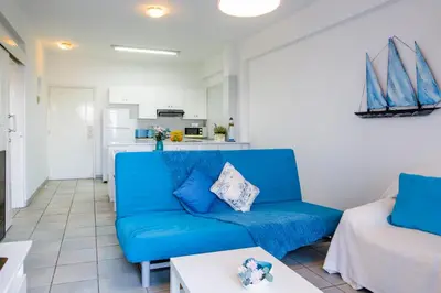 a living room with a blue couch and a table at Krasas Beach Apts in Larnaka