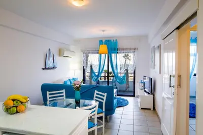 a living room with a blue couch and a table at Krasas Beach Apts in Larnaka