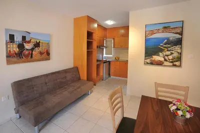 a living room with a couch and a kitchen at Nelia Gardens in Ayia Napa