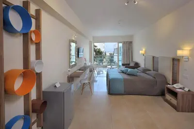 a bedroom with a bed and a desk in a room at Nelia Gardens in Ayia Napa