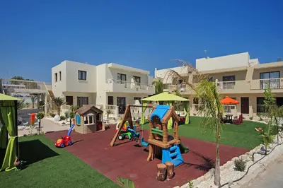 a playground in front of a apartment building with a playground at Nelia Gardens in Ayia Napa