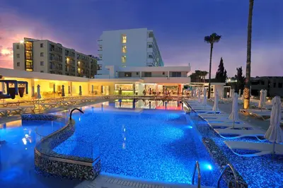 a large swimming pool with chairs and a building at Nelia Beach Hotel & Spa in Ayia Napa