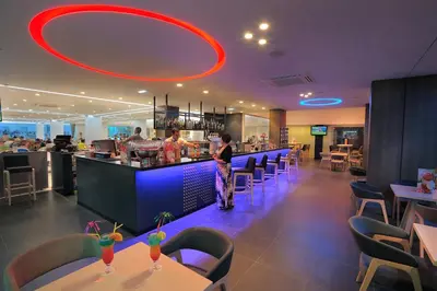 a restaurant with a bar with people preparing food at Nelia Beach Hotel & Spa in Ayia Napa