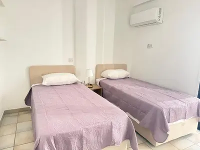 two beds in a room with purple blankets at Krasas Beach Apartments in Larnaka