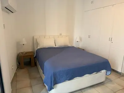 a white bedroom with a bed with a blue blanket at Krasas Beach Apartments in Larnaka