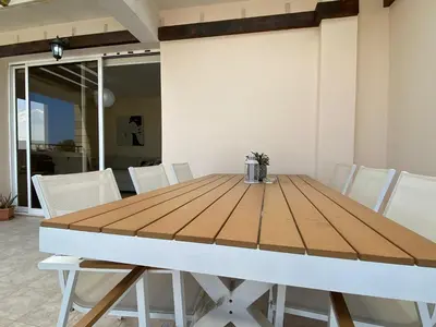 a wooden dining table with white chairs around it at Pyla Palms A1 204 in Pyla