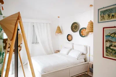 a white bedroom with a bed and some pictures on the wall at Island Home Seaside Villa in Paralimni