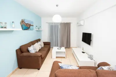a living room with two couches and a tv at Olympia flat 201 in Larnaka