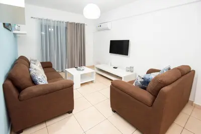 a living room with two chairs and a tv at Olympia flat 201 in Larnaka