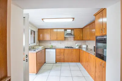a kitchen with wooden cabinets and a white appliance at Villa Dionysos in Protaras