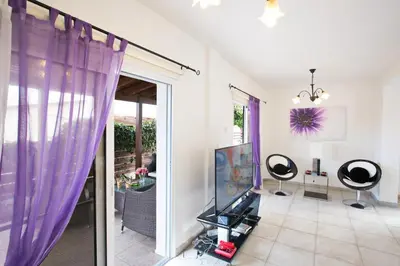 a living room with purple curtains and a tv at Villa Dionysos in Protaras
