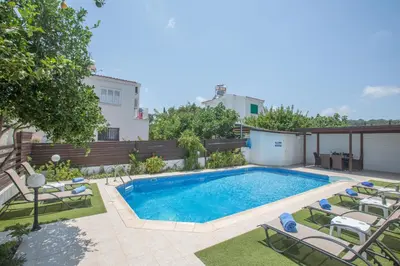 a swimming pool in a backyard with chairs and a house at Villa Dionysos in Protaras