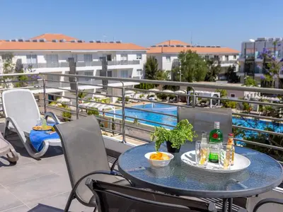 a table and chairs on a balcony with a pool at Mythical Resort by KARMA in Paralimni