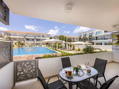 a balcony with a table and chairs and a swimming pool at Mythical Resort by KARMA in Paralimni